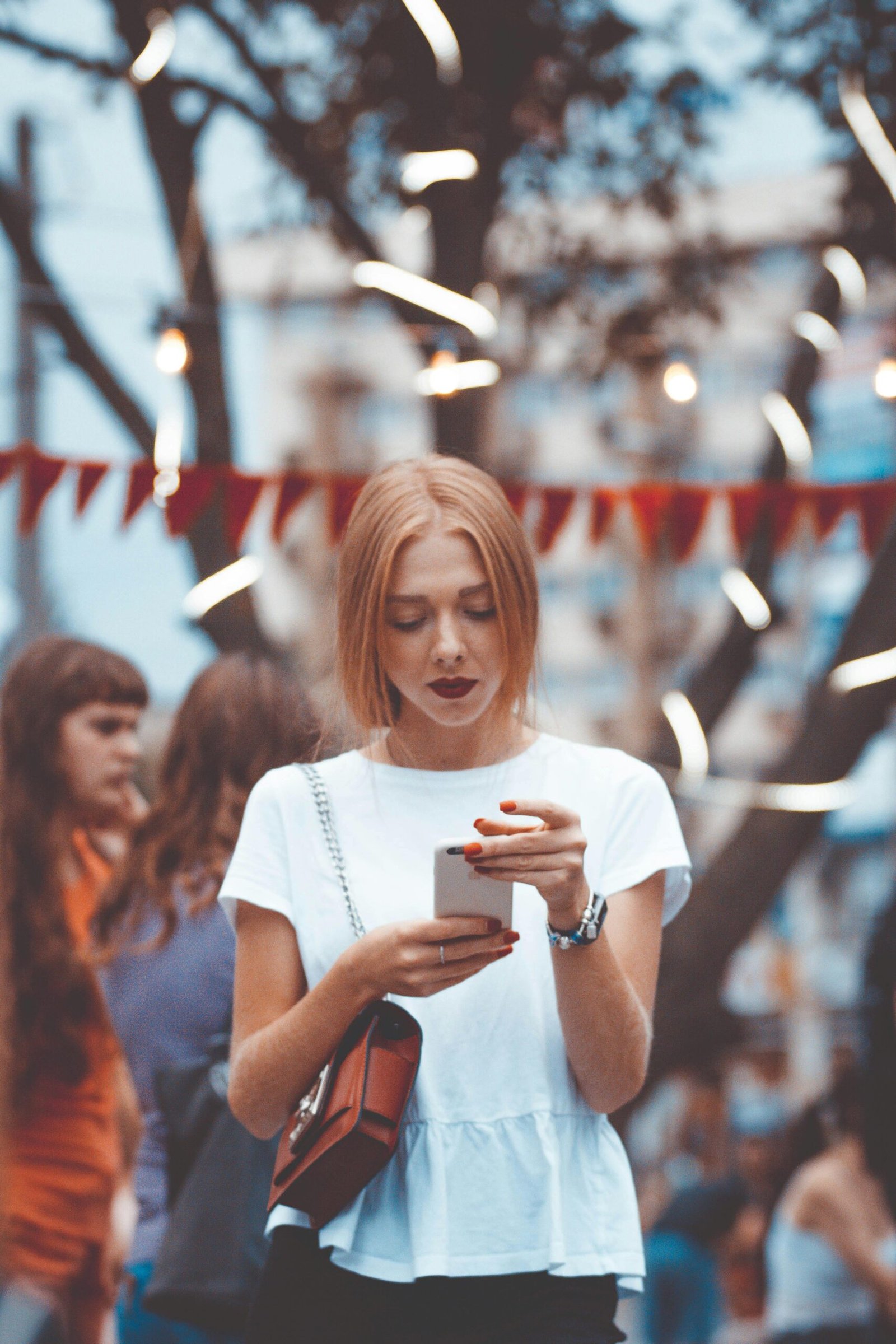 Young woman engrossed in smartphone amidst lights and bokeh in Chernivtsi street.